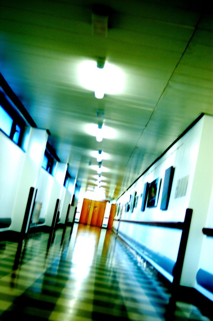 Patients resting in a bright hospital ward with large windows and natural daylight.
